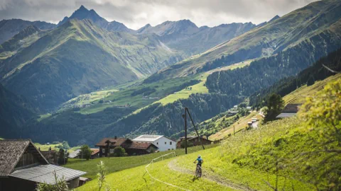 Biker über Dorf vor Bergkulisse