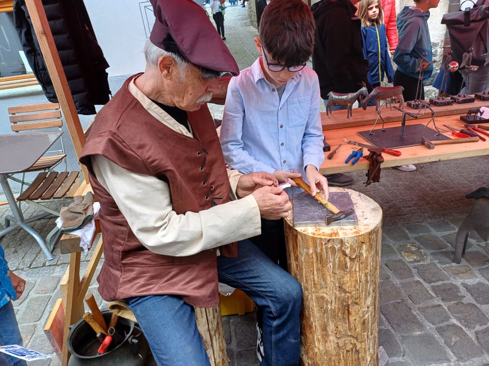 Älterer Mann und Junge bearbeiten Holz an einem Marktstand.