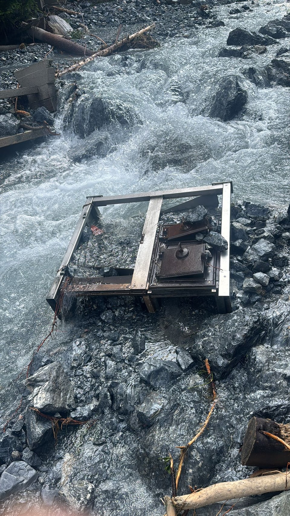 Bach mit Metallrahmen und Holztüren auf Felsen.