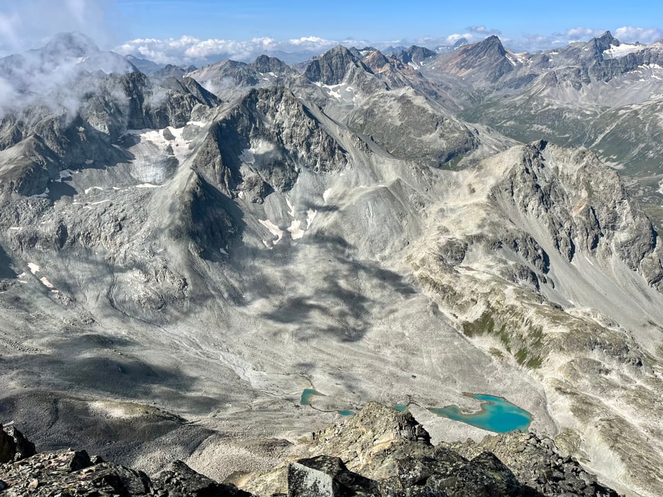 Blick auf schroffe Berglandschaft mit blauem Gletschersee.