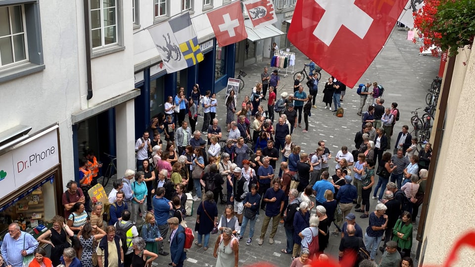 Menschenmenge in einer engen Strasse mit schweizerischen Fahnen.