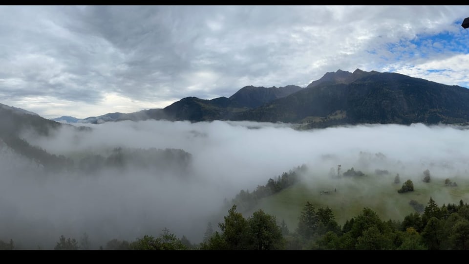 Nebelüberzogene Berge und Wälder unter bewölktem Himmel.