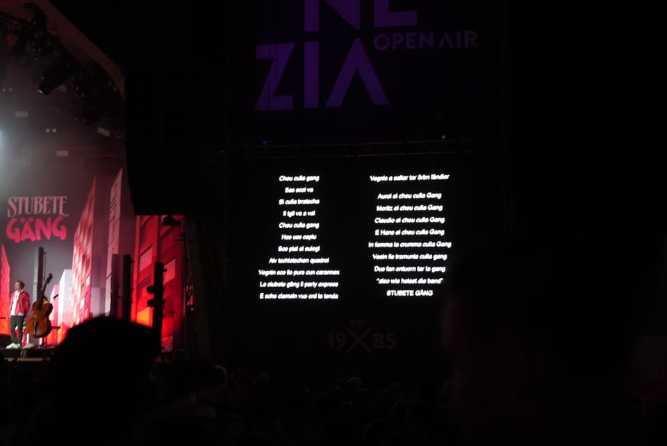 Nachtaufnahme einer Konzertbühne mit grossem Bildschirm und Live-Performance am Open Air Lumnezia..