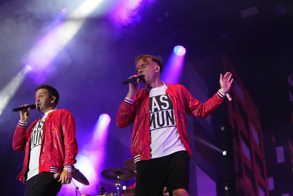 Zwei Sänger in roten Jacken auf einer Bühne mit Mikrofonen am Open Air Lumnezia 2024..
