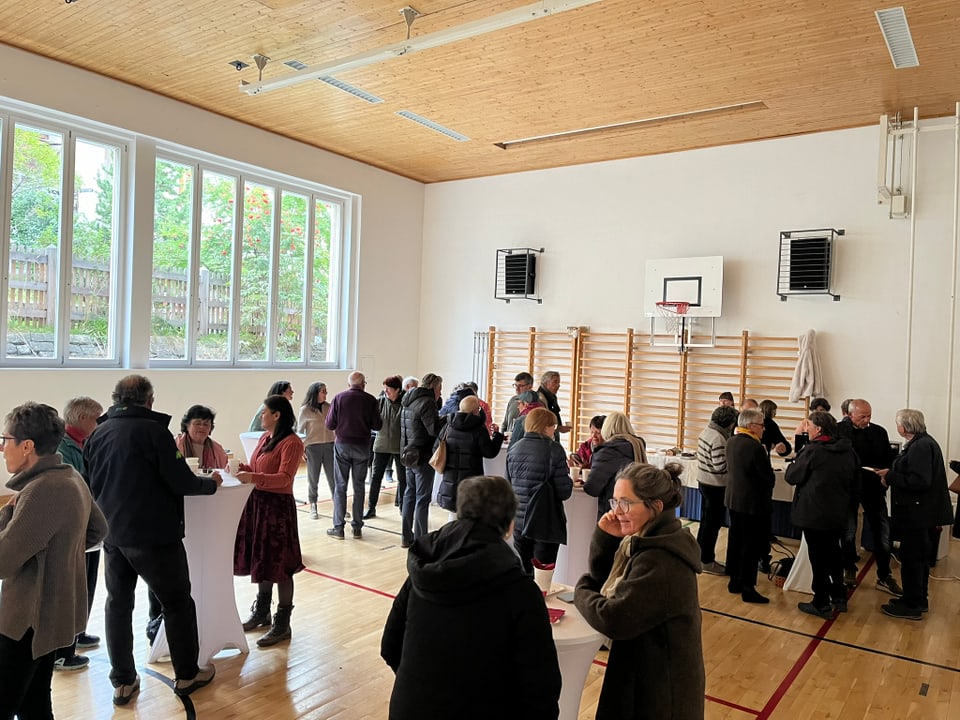 Menschen, die sich in einer Turnhalle unterhalten.