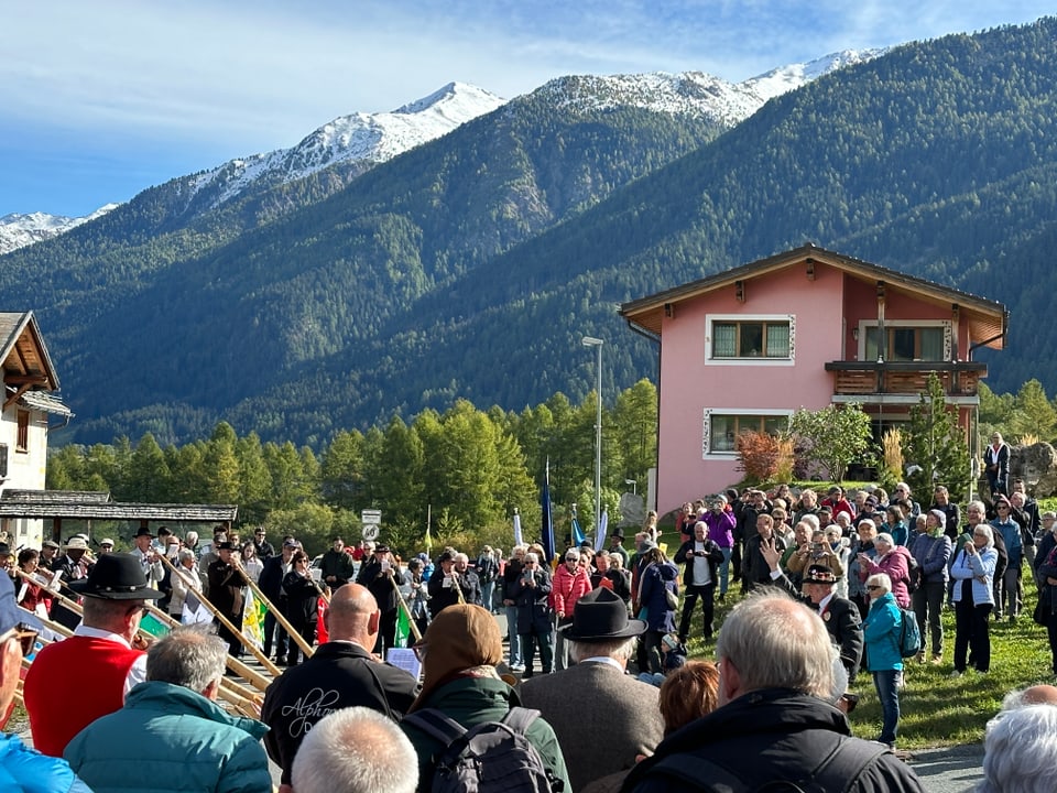 Menschenmenge vor Alpenkulisse mit schneebedeckten Bergen.