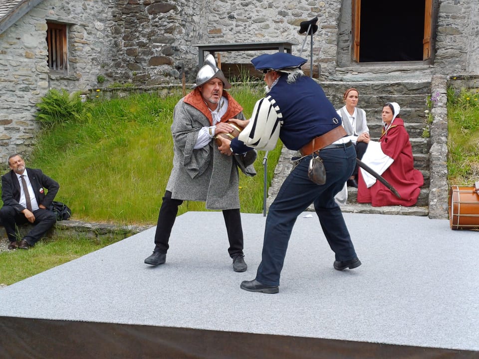 Mittelalterliche Schauspieler kämpfen auf einer Bühne.