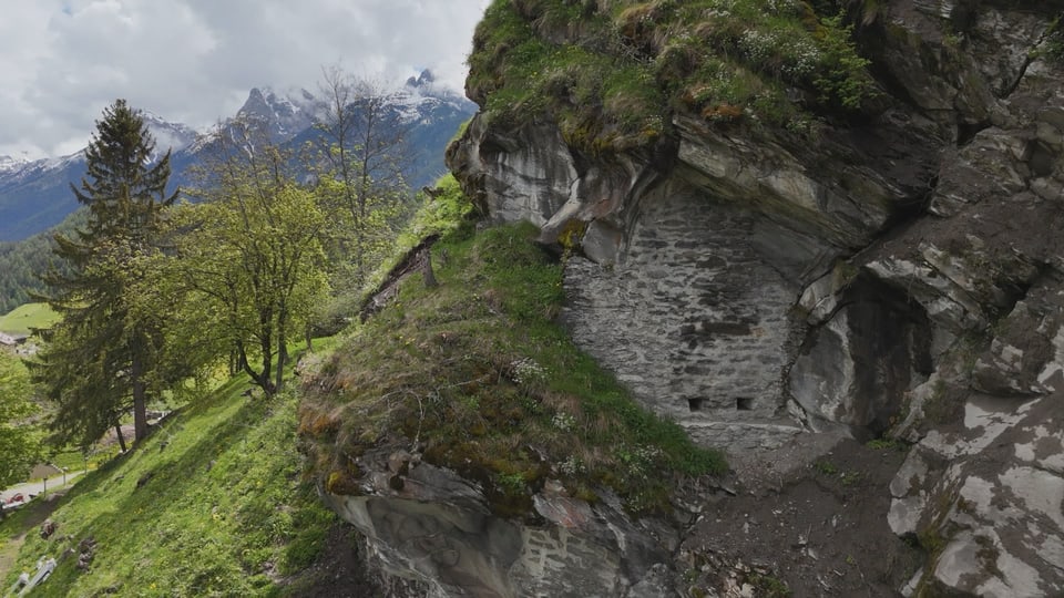 Steinmauer in einem Felsen mit Bergkulisse im Hintergrund.