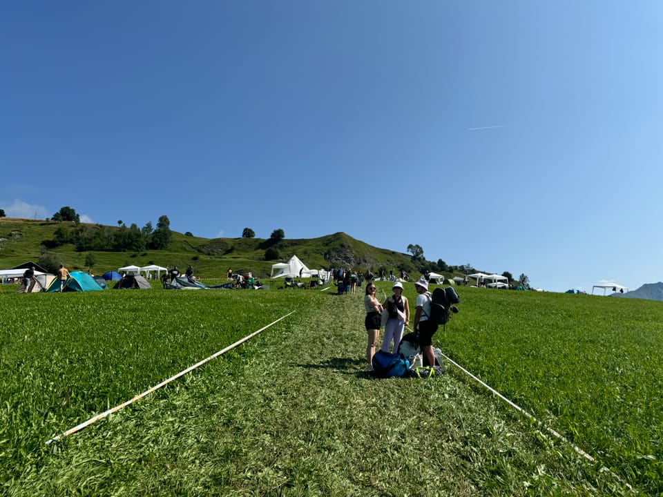 Campingszene auf einem Hügel bei sonnigem Wetter am Open Air Lumnezia 2024.
