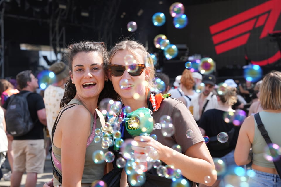 Zwei Frauen lächeln inmitten von Seifenblasen auf einem Festival am Open Air Lumnezia 2024.