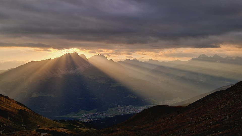 Sonnenstrahlen über Berglandschaft bei Sonnenuntergang.