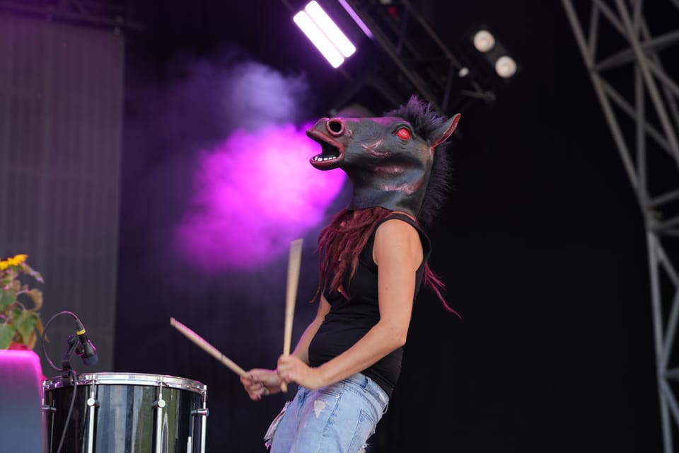 Person im Pferdekostüm spielt Schlagzeug auf der Bühne.