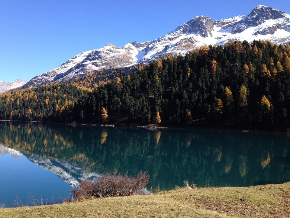 Schneebedeckte Berge spiegeln sich in klarem See.