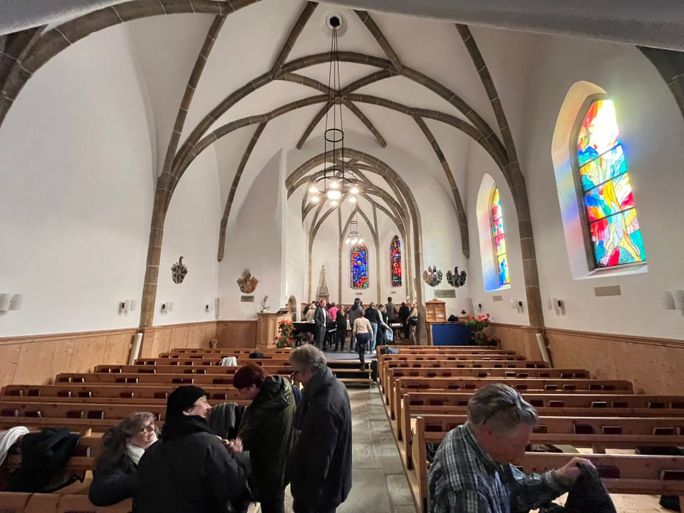 Menschen in einer Kirche mit bunten Glasfenstern.