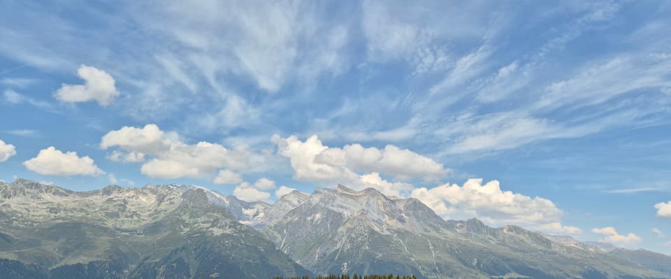 Panoramablick auf bewölkte Alpenlandschaft.