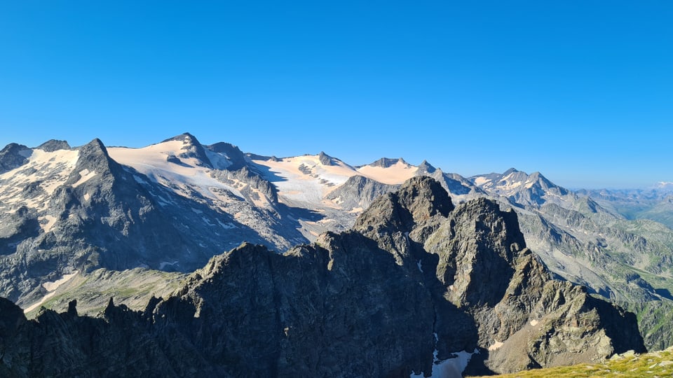 Panoramablick auf schneebedeckte Berggipfel unter blauem Himmel.