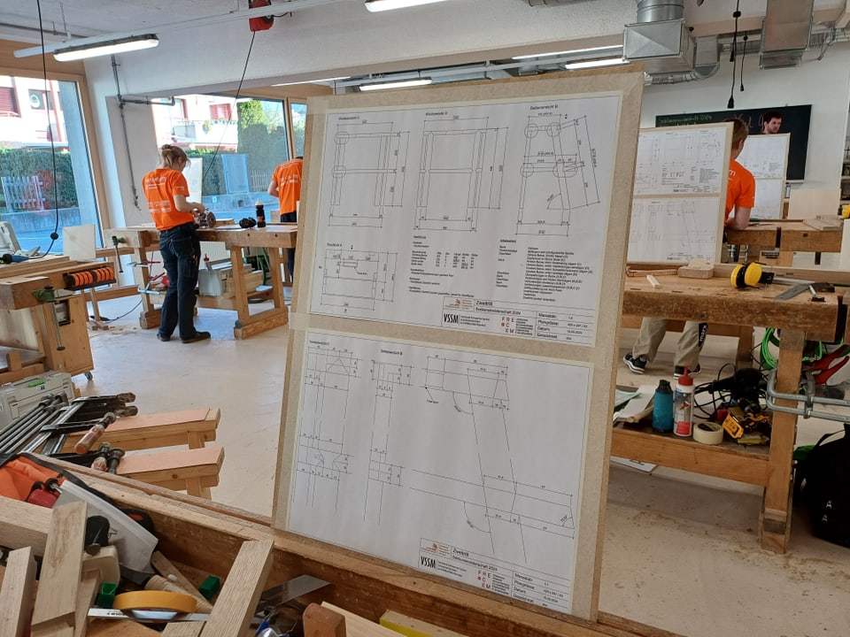 Arbeitsraum mit technischen Zeichnungen und Holzbearbeitungswerkzeugen.