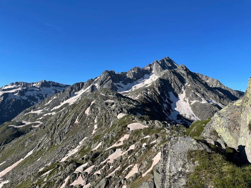 Alpenlandschaft mit schneebedeckten Bergen unter klarem Himmel.