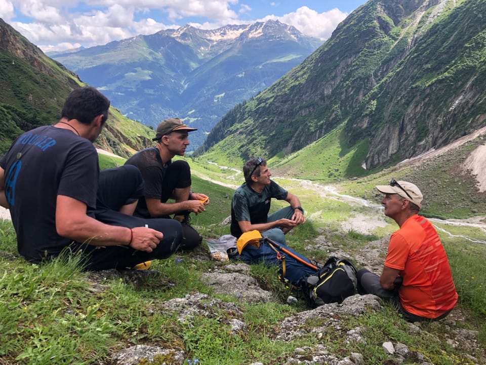 Vier Männer machen eine Pause beim Wandern in den Bergen.