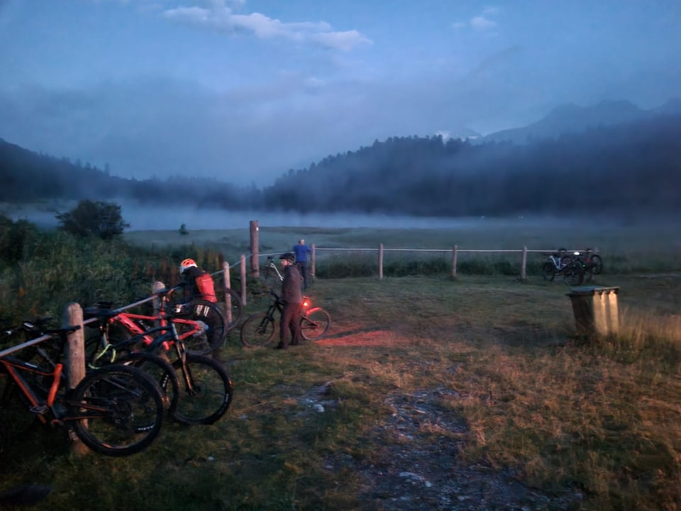 Radfahrer bei Sonnenaufgang in nebliger Landschaft.