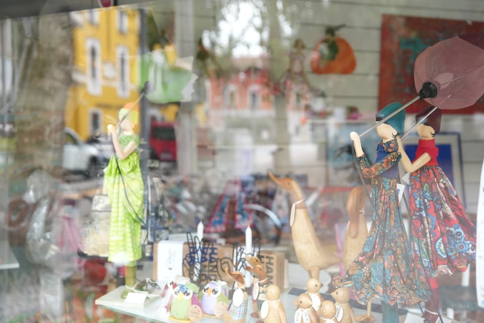 Schaufenster mit dekorativen Figuren und bunten Stoffen.