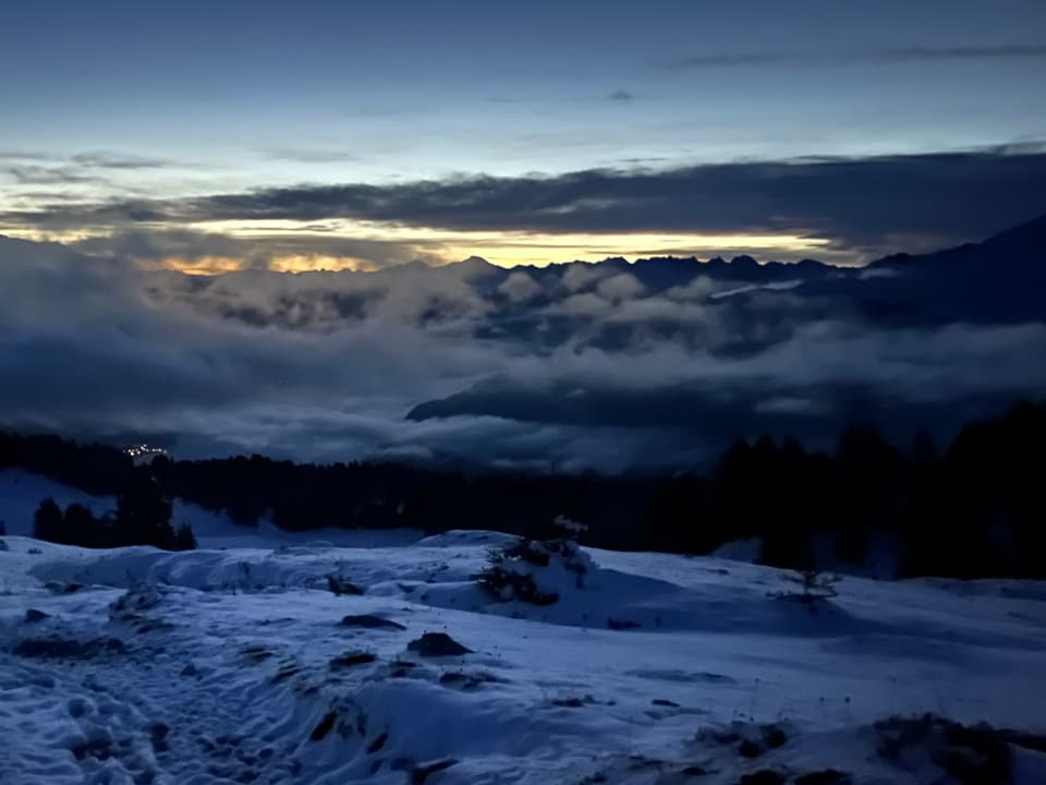 Verschneite Berglandschaft bei Sonnenuntergang mit Wolken.