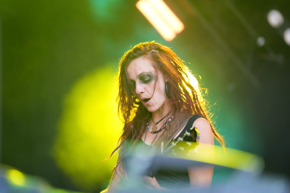 Frau mit Gitarre auf der Bühne in gelbem Licht am Open Air Lumnezia 2024 in Degen.