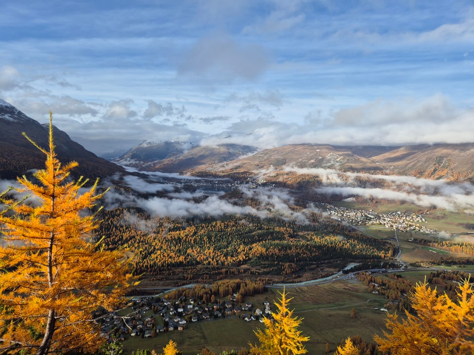 Herbstliche Berglandschaft mit Nebel und Dörfern in den Alpen.