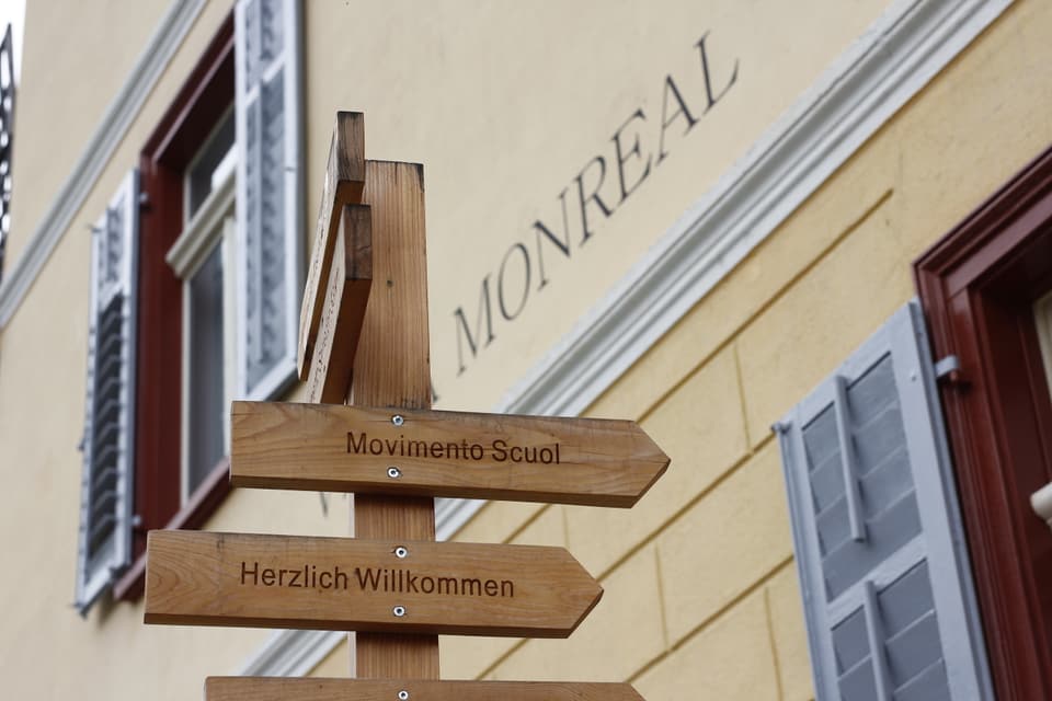 Movimento Scuol: Holzwegweiser mit der Aufschrift 'Herzlich Willkommen' vor einem Gebäude in Montréal.