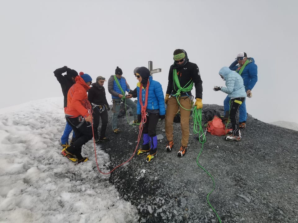 Besteigung Piz Russein / Tödi: Bergsteigergruppe mit Seilen auf schneebedecktem Gipfel.