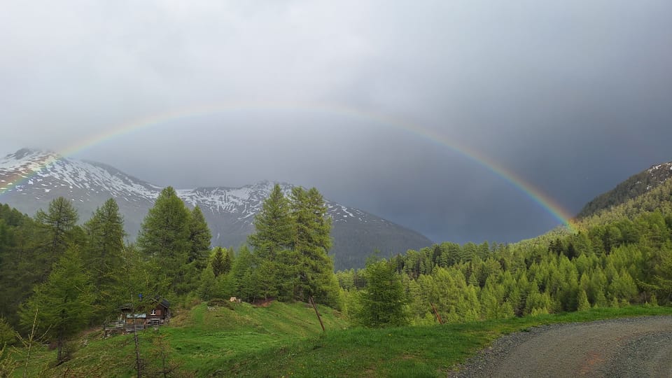 Regenbogen über einem Wald in den Bergen.