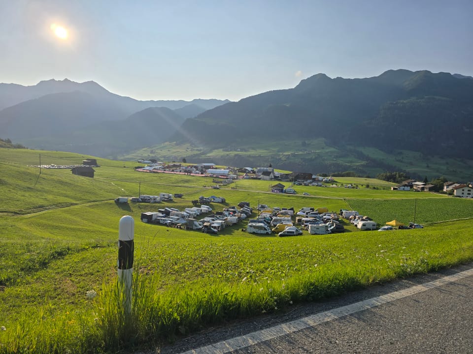Campingplatz auf grünen Hügeln mit Bergen im Hintergrund.