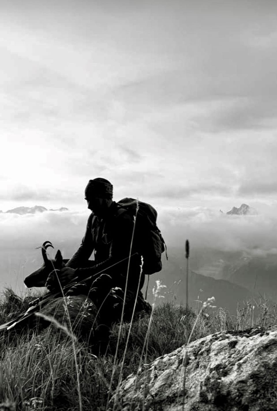 Schwarzweissaufnahme eines Wanderers auf einem Berggipfel.