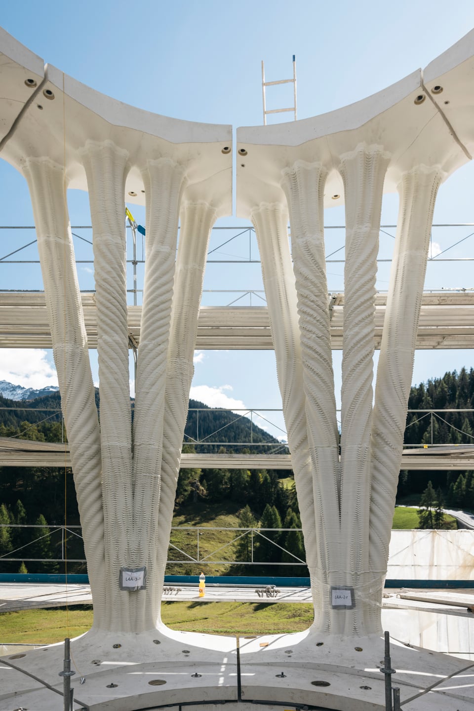 Baustelle eines modernen Betongerüsts vor Berglandschaft.