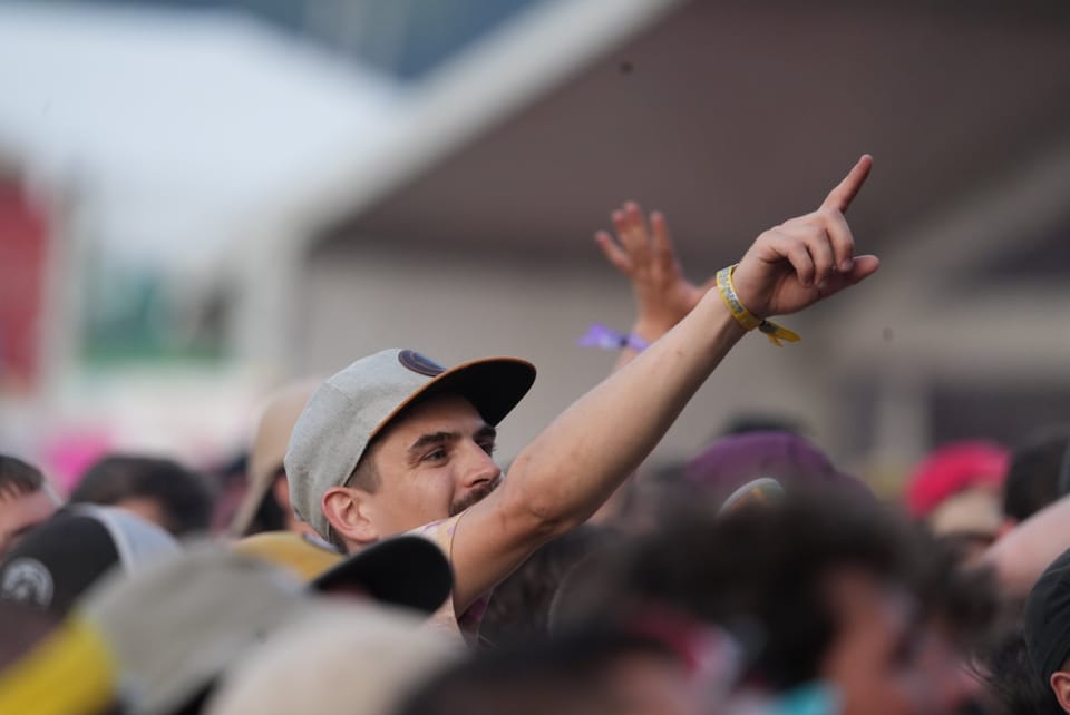 Mann mit grauer Mütze zeigt während einer Menschenmenge nach oben.