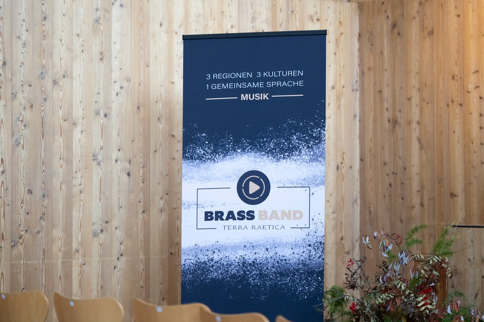 Banner der Brass Band Terra Raetica vor Holzwand und Stühlen.