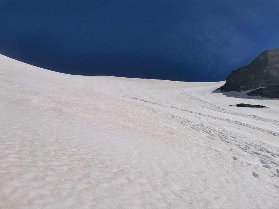 Besteigung Piz Russein / Tödi: Verschneiter Berghang unter blauem Himmel.