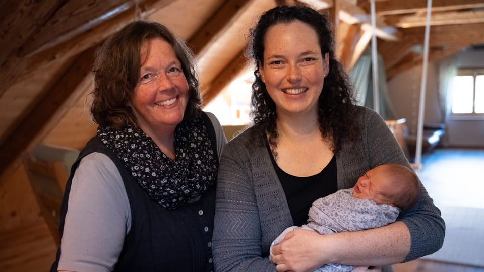 Zwei Frauen mit einem Baby in einem Dachzimmer.