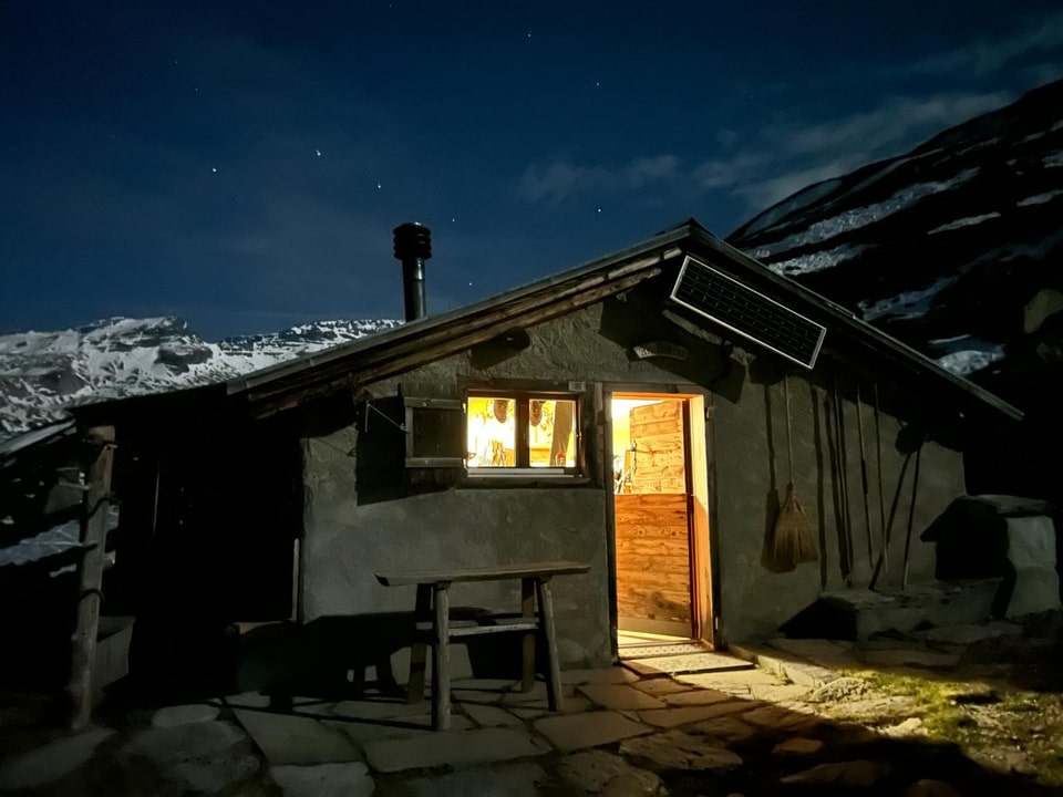 Beleuchtete Hütte bei Nacht in den Bergen.