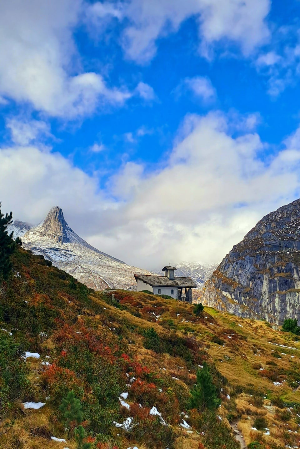 Hütte in alpiner Berglandschaft mit blauem Himmel.