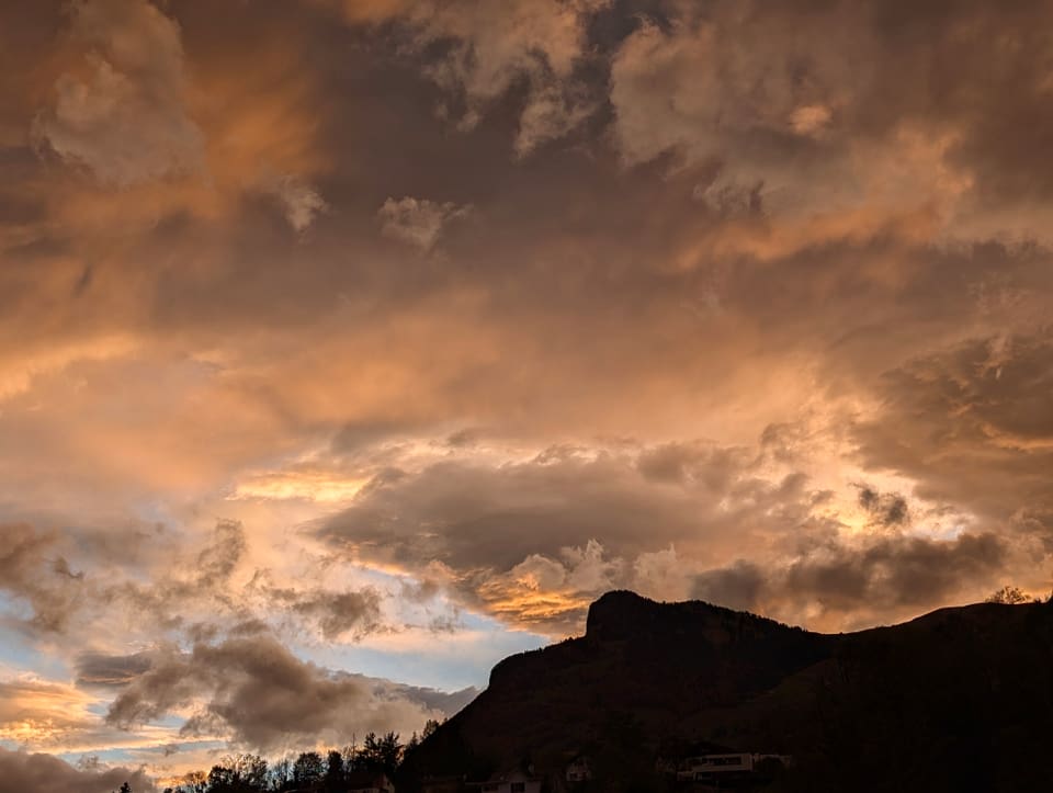 Dramatischer Himmel mit Wolken über Berg bei Sonnenuntergang.