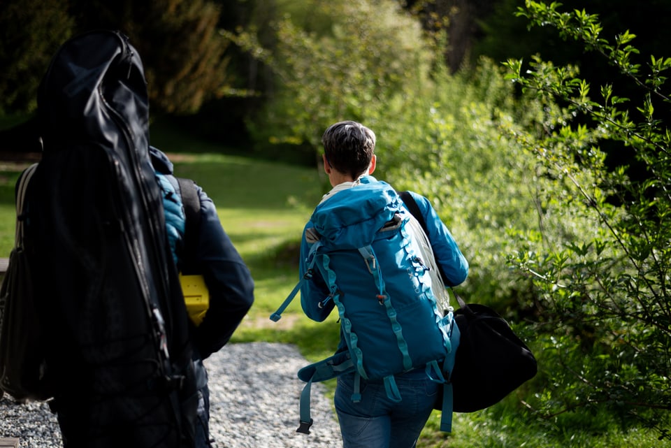 Zwei Personen mit Rucksäcken laufen im Wald.