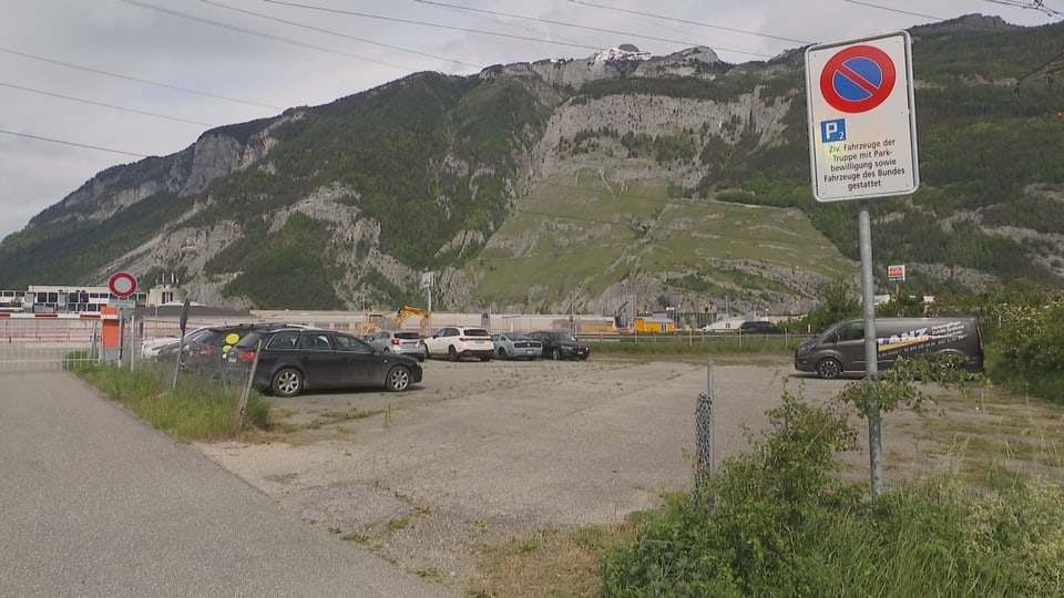 Auto-Parkplatz mit Berghintergrund und Parkverbotschild.