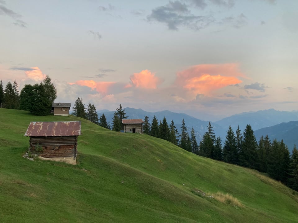 rosarote Nebel in Trin hinter einer Berghütte