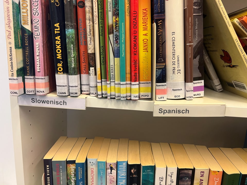 Regal mit Büchern in slowenischer und spanischer Sprache.