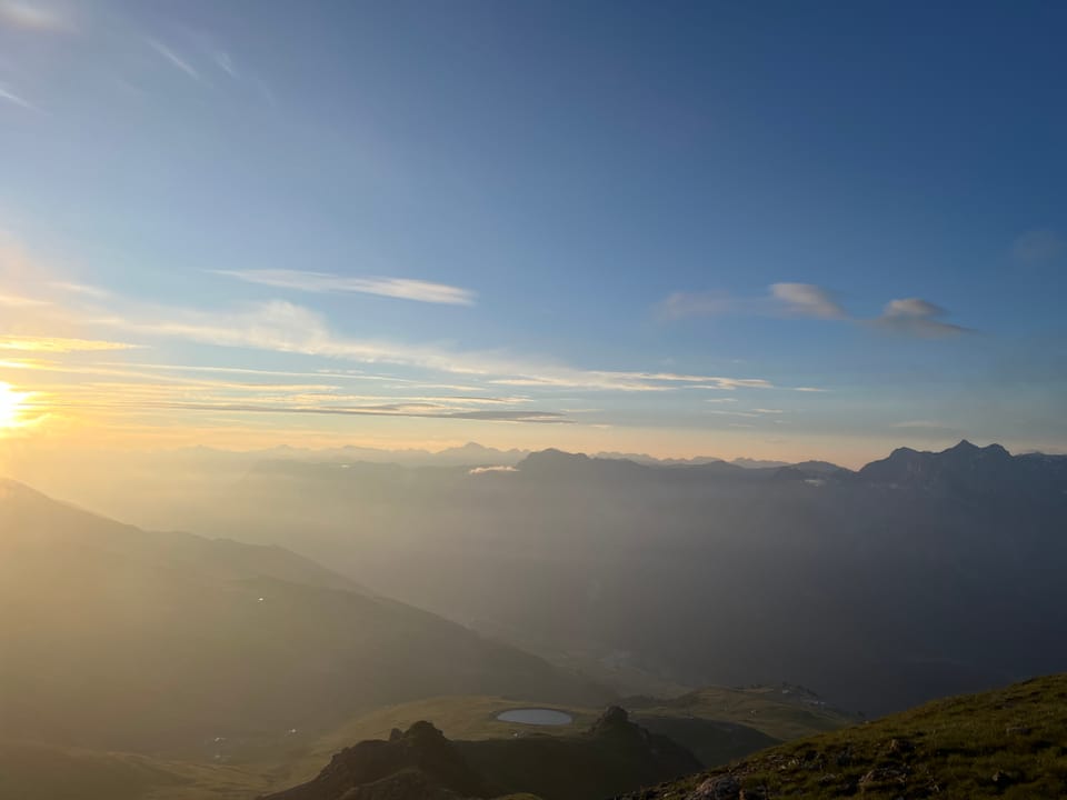 Sonnenaufgang in den Bergen mit Blick auf nebliges Tal.