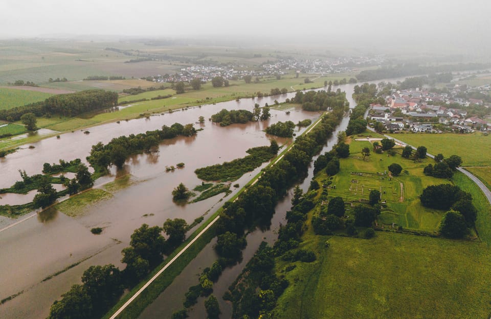 Luftaufnahme einer überschwemmten ländlichen Gegend mit einem Fluss und Feldern.