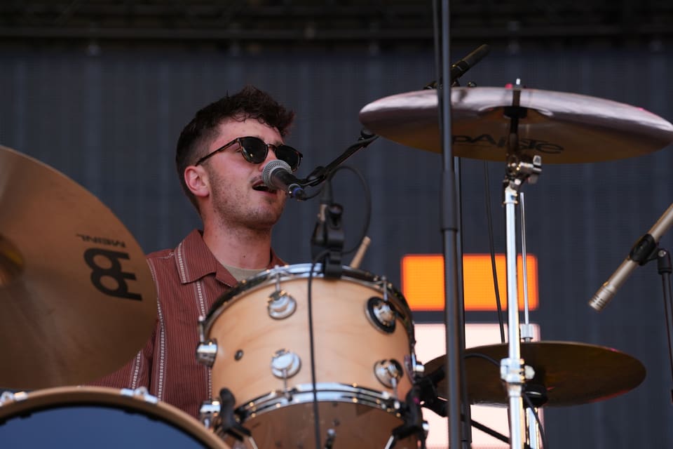 Schlagzeuger mit Sonnenbrille beim Singen auf der Bühne am Open Air Lumnezia 2024.