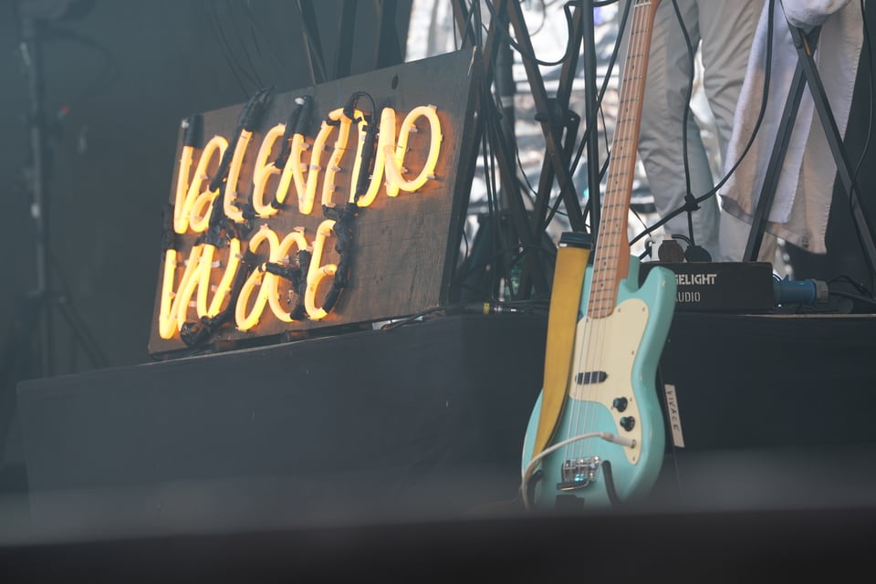 Neonlichtschild und E-Gitarre auf Bühne am Open Air Lumnezia 2024.