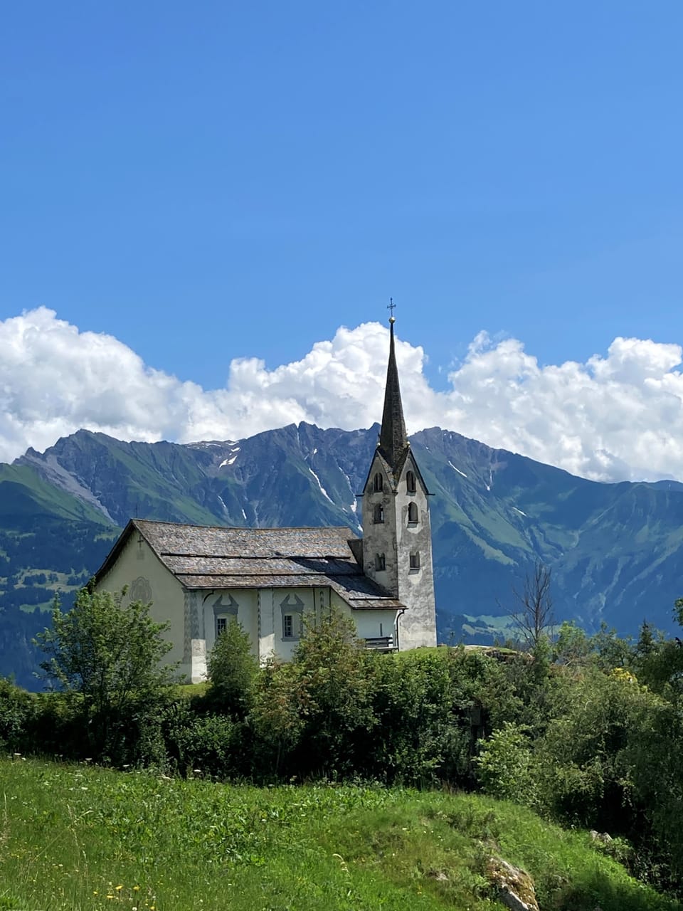 Kirche auf einem Hügel mit Bergblick.